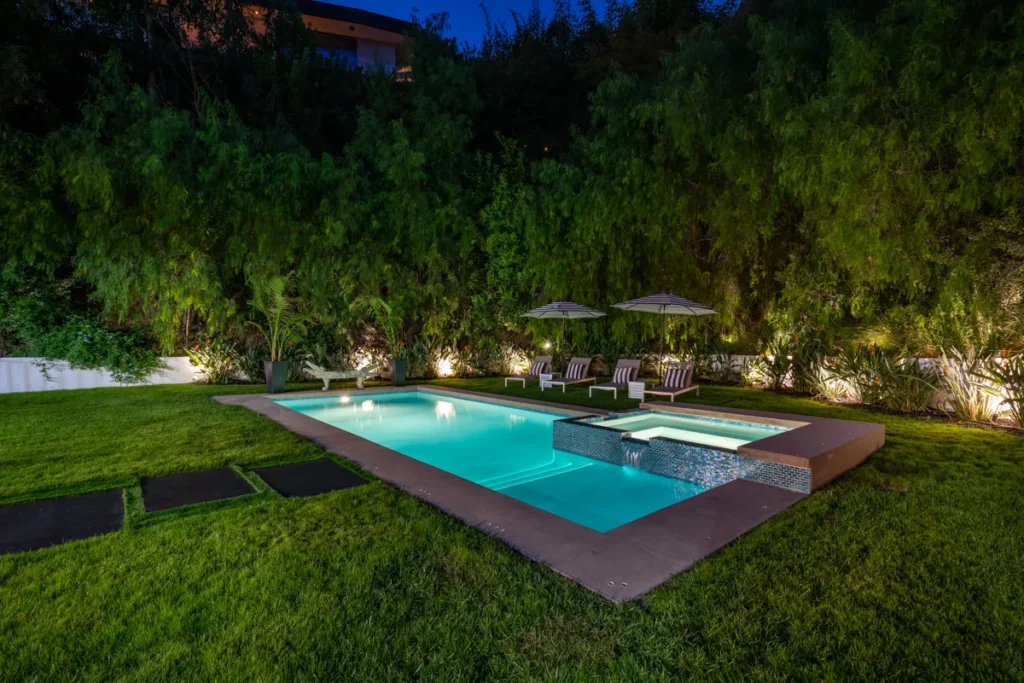Luxury Hollywood Hills backyard patio with poolside seating at dusk.